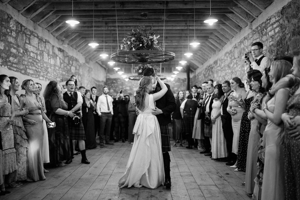 Editorial wedding photography Scotland bride and groom first dance surrounded by guests rustic venue